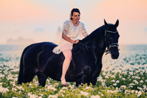 Reiterin auf schwarzem Pferd im Sonnenaufgang